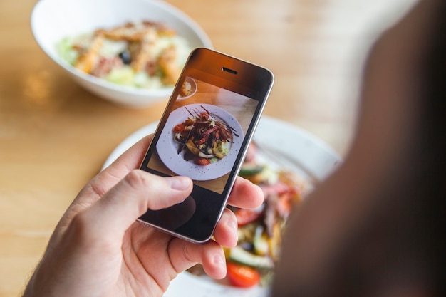 Foto un hombre fotografía una deliciosa ensalada en su teléfono en un restaurante