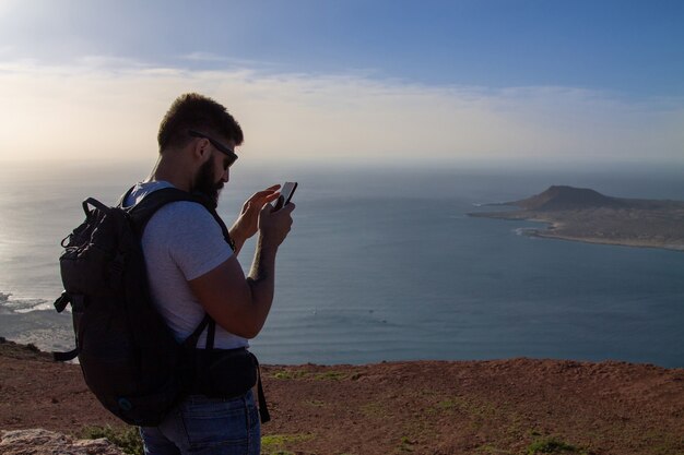 El hombre fotografía una isla en el océano, al borde de un acantilado. Mirador del Rio, Lanzarote, España.