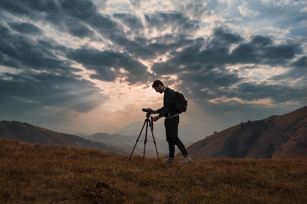 Hombre fotografiando en la cámara contra el cielo durante la puesta de sol