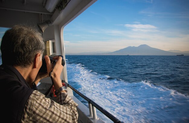 Foto hombre fotografiando el mar contra el cielo