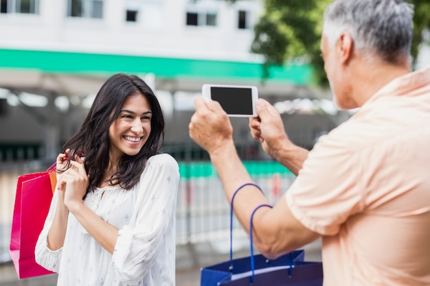 Hombre fotografiando mujer con bolsa de compras