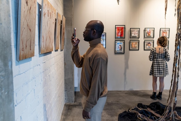 Foto hombre fotografiando obras de arte por teléfono