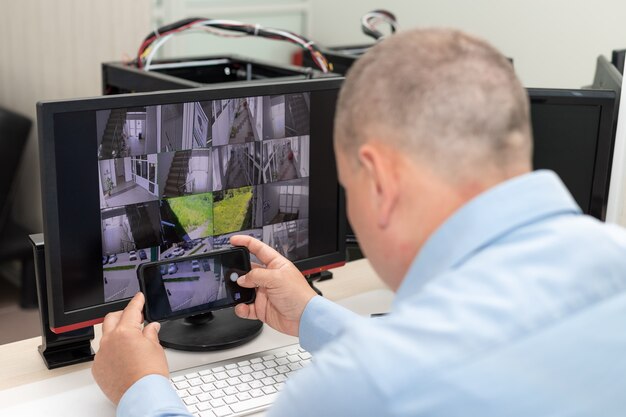 Hombre fotografiando varios monitores en la sala de vigilancia Gestión CCTV