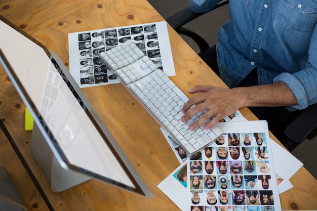 Foto hombre con fotografías trabajando en pc de escritorio