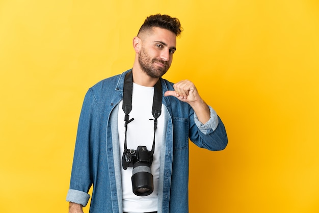 Foto hombre fotógrafo aislado sobre fondo amarillo orgulloso y satisfecho de sí mismo