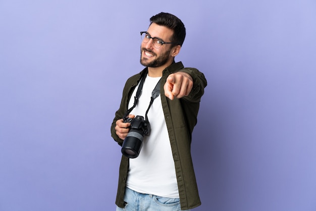 Hombre fotógrafo en frente apuntando púrpura aislado con expresión feliz