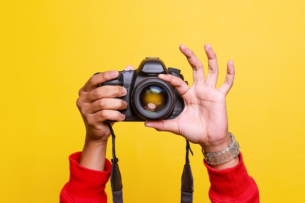 Hombre fotógrafo hace fotos Las manos masculinas sostienen el primer plano de la cámara y ajustan la lente