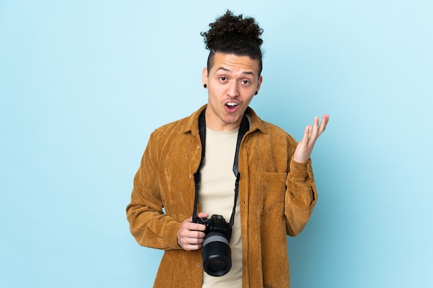 Hombre fotógrafo sobre azul aislado con expresión facial sorpresa