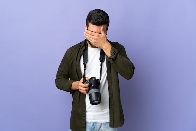 Hombre fotógrafo sobre fondo púrpura aislado con expresión cansada y enferma