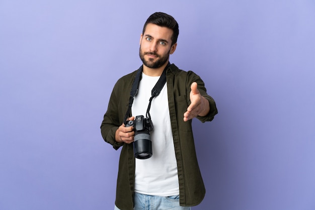 Hombre fotógrafo sobre pared púrpura aislada estrecharme la mano para cerrar un buen trato