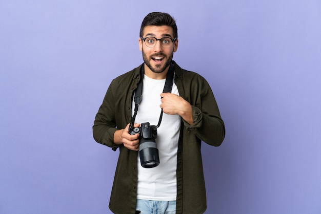 Hombre fotógrafo sobre pared púrpura aislada con expresión facial sorpresa