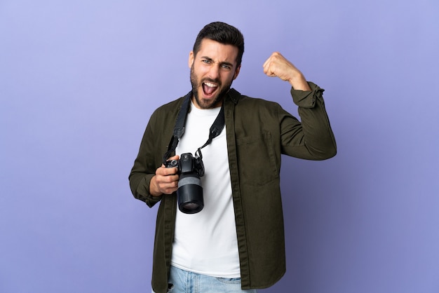 Hombre fotógrafo sobre pared púrpura aislada haciendo gesto fuerte