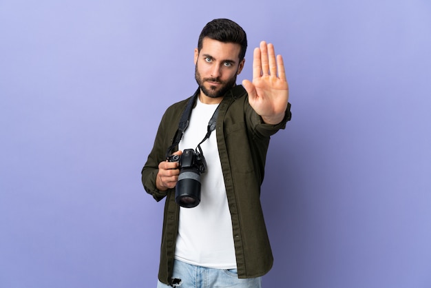 Hombre fotógrafo sobre pared púrpura aislada haciendo gesto de parada