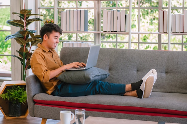 Hombre freelance usando laptop para trabajar en casa en el sofá