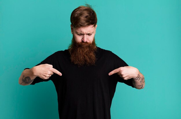 Hombre fresco de barba larga y cabello rojo con una camisa simple y con un espacio de copia