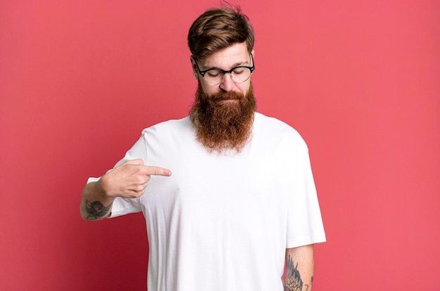 Hombre fresco de barba larga y cabello rojo con una camisa simple y con un espacio de copia