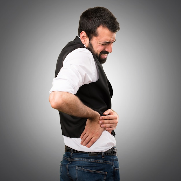 Hombre fresco con dolor de espalda sobre fondo gris