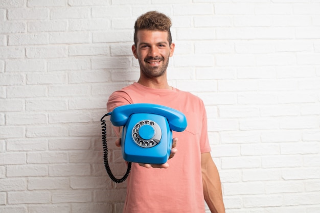 Hombre fresco hermoso joven que sostiene un teléfono de la vendimia