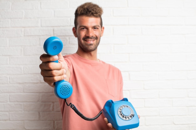 Hombre fresco hermoso joven que sostiene un teléfono de la vendimia