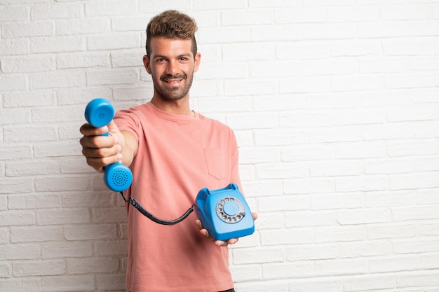 Hombre fresco hermoso joven que sostiene un teléfono de la vendimia