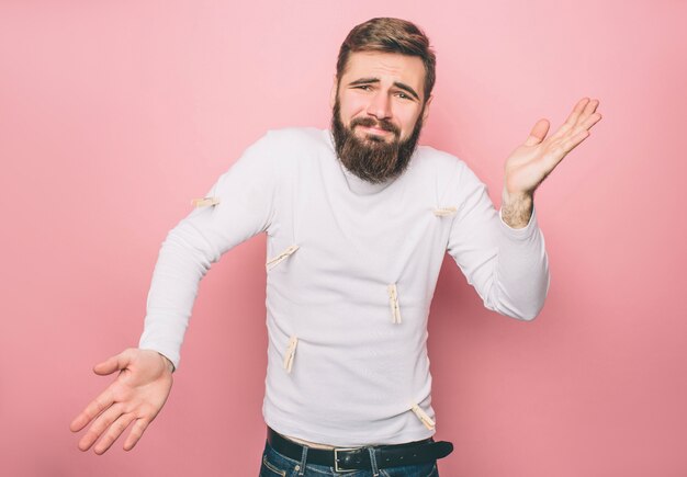 El hombre frustrado está de pie cerca de la pared rosada.