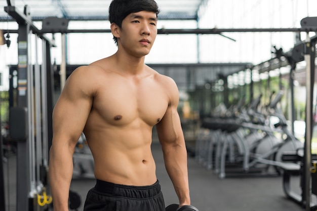 hombre fuerte aptitud posando cuerpo musculoso y haciendo ejercicios para culturista en el gimnasio