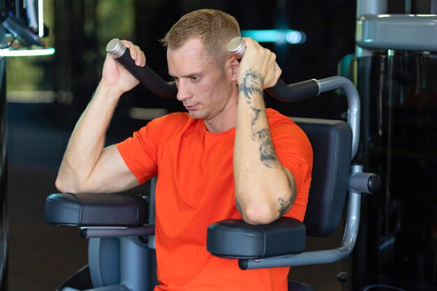 Hombre fuerte atleta bombeo de los músculos en el gimnasio. entrenamiento de chico musculoso. ejercicios para bíceps, manos, espalda. deportes, fitness.