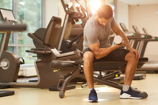 Hombre fuerte bombeo de músculos en el gimnasio