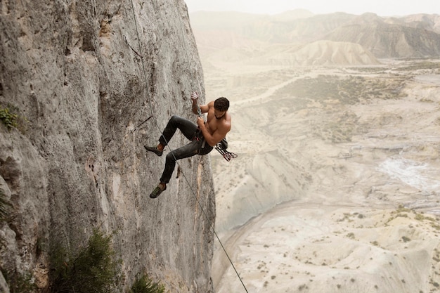 Foto hombre fuerte escalada en una montaña con equipo de seguridad