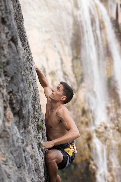 Hombre fuerte escalada en una montaña con equipo de seguridad