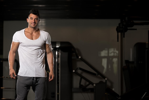 Hombre fuerte en gimnasio de fondo de camiseta blanca