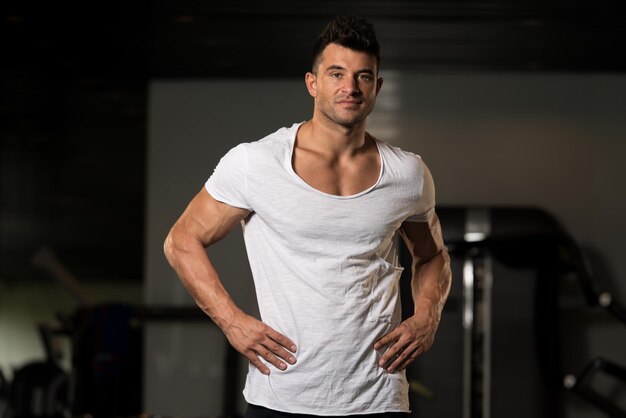 Hombre fuerte en gimnasio de fondo de camiseta blanca