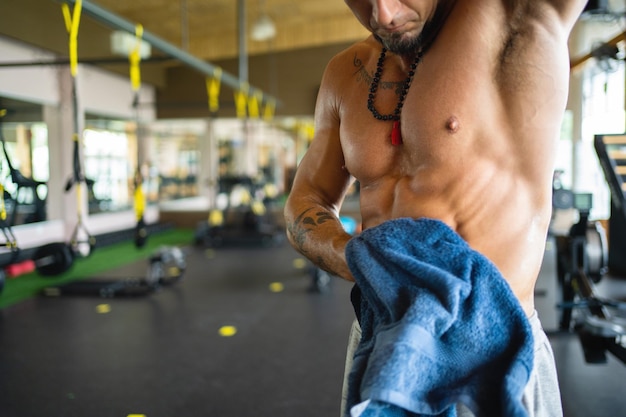 Hombre fuerte en un gimnasio secándose con una toalla