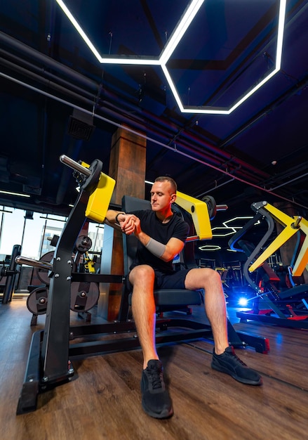 Hombre fuerte y guapo haciendo ejercicio en el gimnasio Entrenamiento de atleta musculoso en un gimnasio moderno