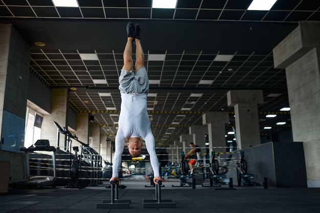 Hombre fuerte haciendo ejercicio, entrenamiento físico en el gimnasio