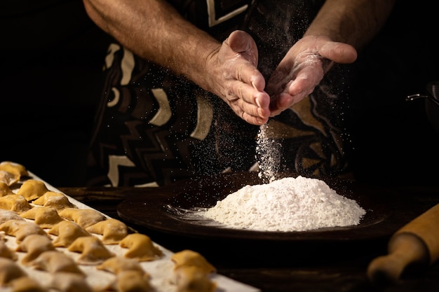 Hombre fuerte manos espolvorear bolas de masa de harina plato nacional ucraniano