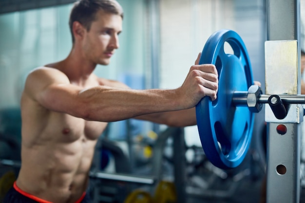 Foto hombre fuerte montaje de barra en el gimnasio