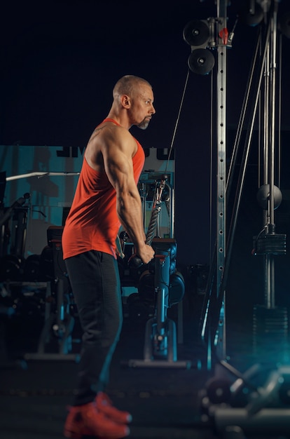 El hombre fuerte y musculoso entrena en el gimnasio.