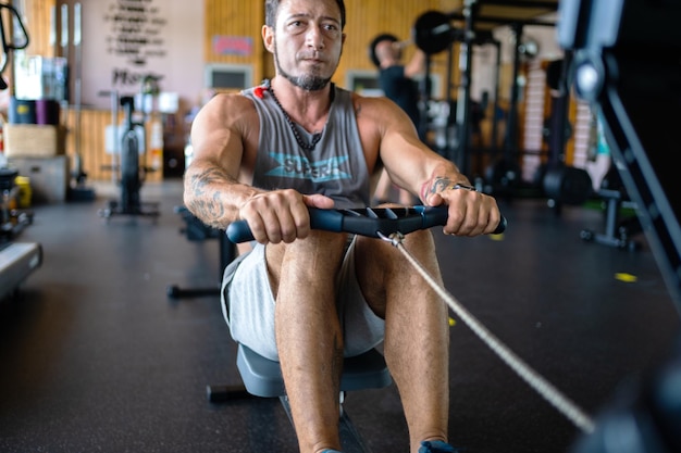 Hombre fuerte remando en una máquina en un gimnasio