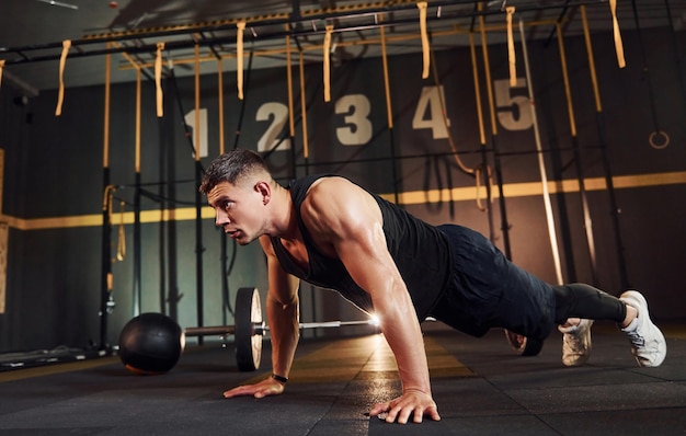 Hombre fuerte con ropa deportiva haciendo flexiones en el gimnasio