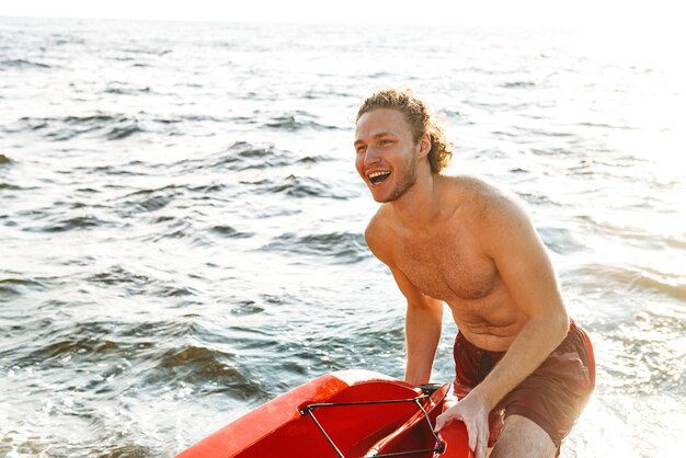 Hombre fuerte sano en kayak en el mar, preparándose