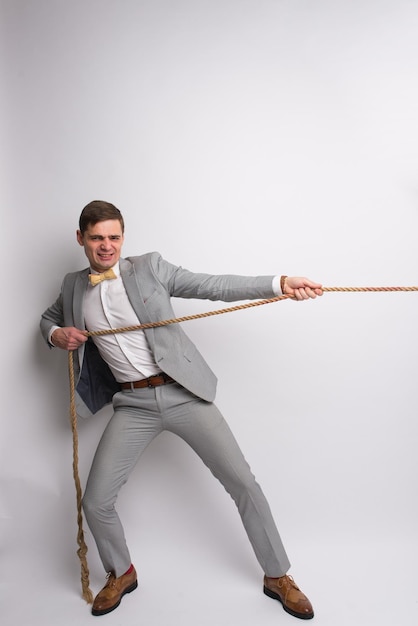 Hombre fuerte tirando de la cuerda Foto de hombre deportivo sobre fondo gris Fuerza y motivación