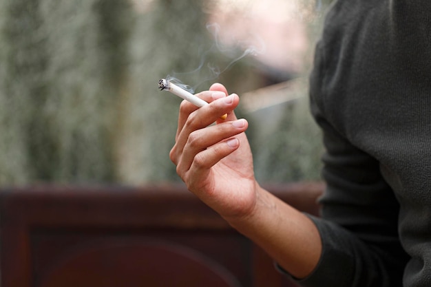 Hombre fumando un cigarrillo en la mano