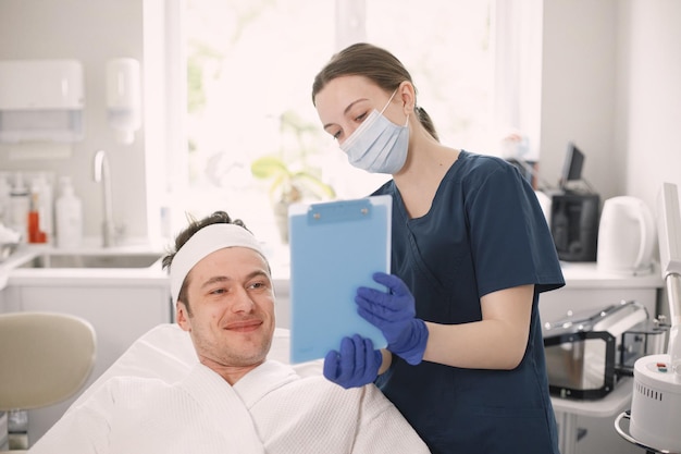 El hombre en el gabinete de la cosmetóloga va a recibir un procedimiento de cuidado de la piel