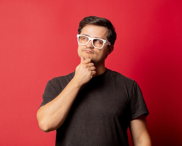 Hombre de gafas y camisa en espacio rojo