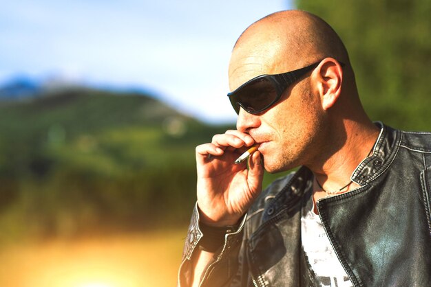 Hombre con gafas y chaqueta negra fumando cigarrillo