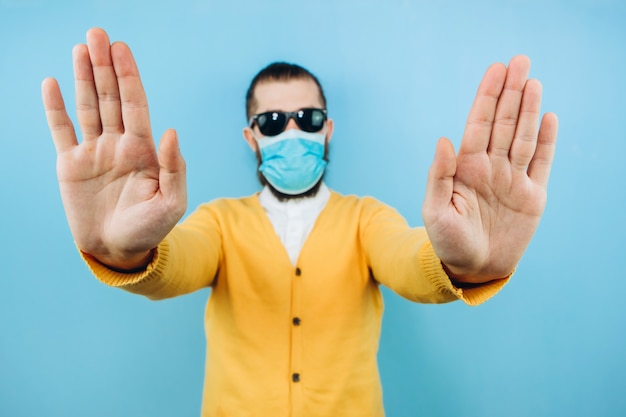 Foto un hombre con gafas y una máscara médica. un chico emocional y positivo en el autoaislamiento. coronavirus. estudio de rodaje. pandemia covid 19.