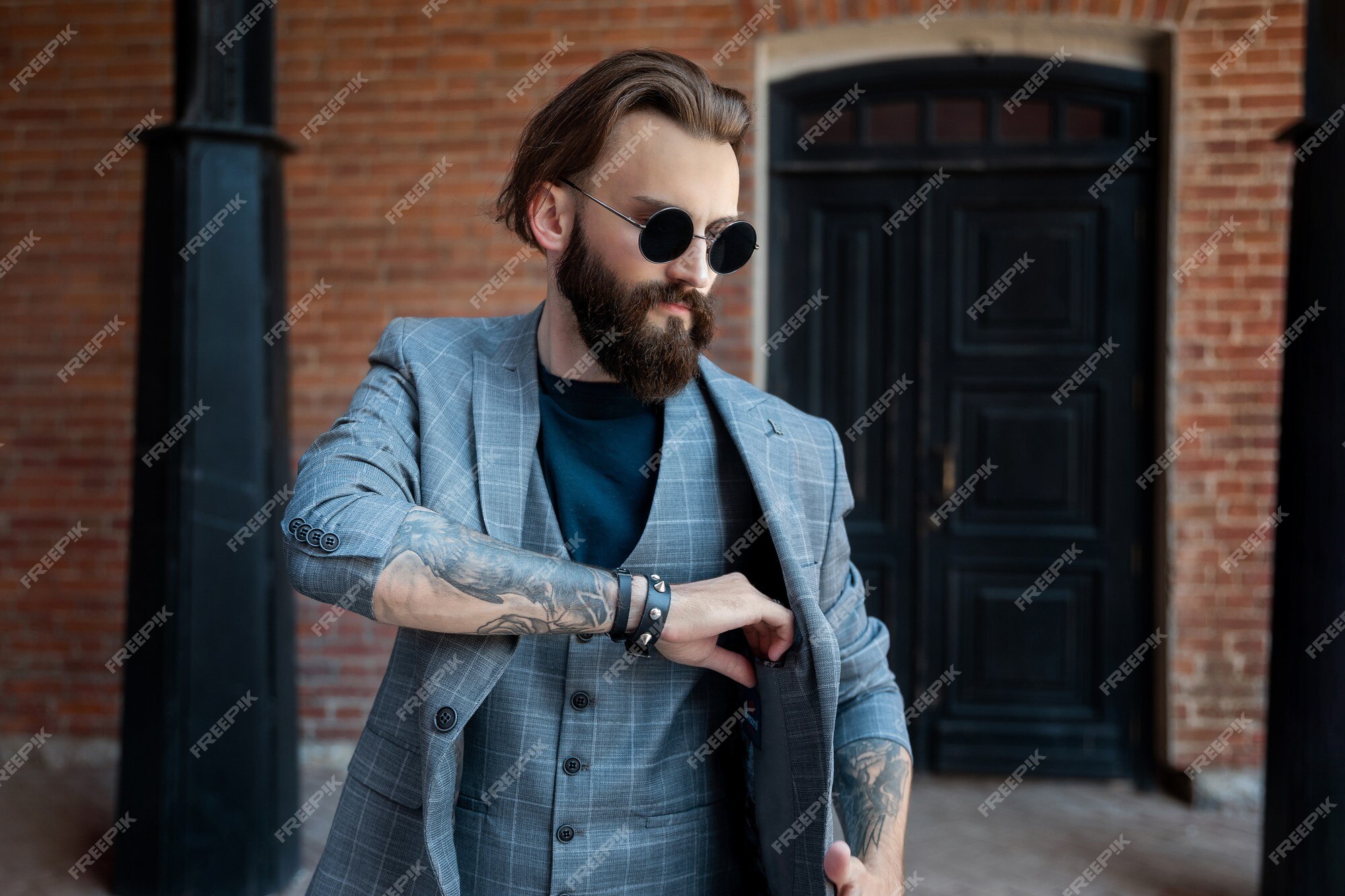 Hombre gafas y una chaqueta gris un edificio de ladrillo | Foto Premium