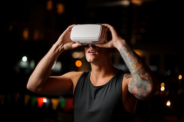 Hombre con gafas de realidad virtual contra la ciudad de noche