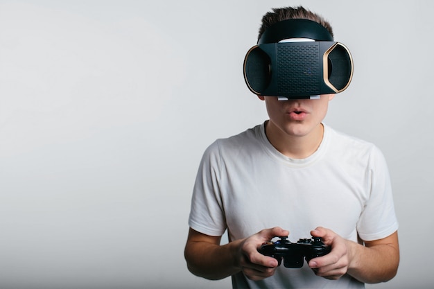 Hombre con gafas de realidad virtual y sosteniendo un gamepad mientras está de pie cerca de la pizarra blanca